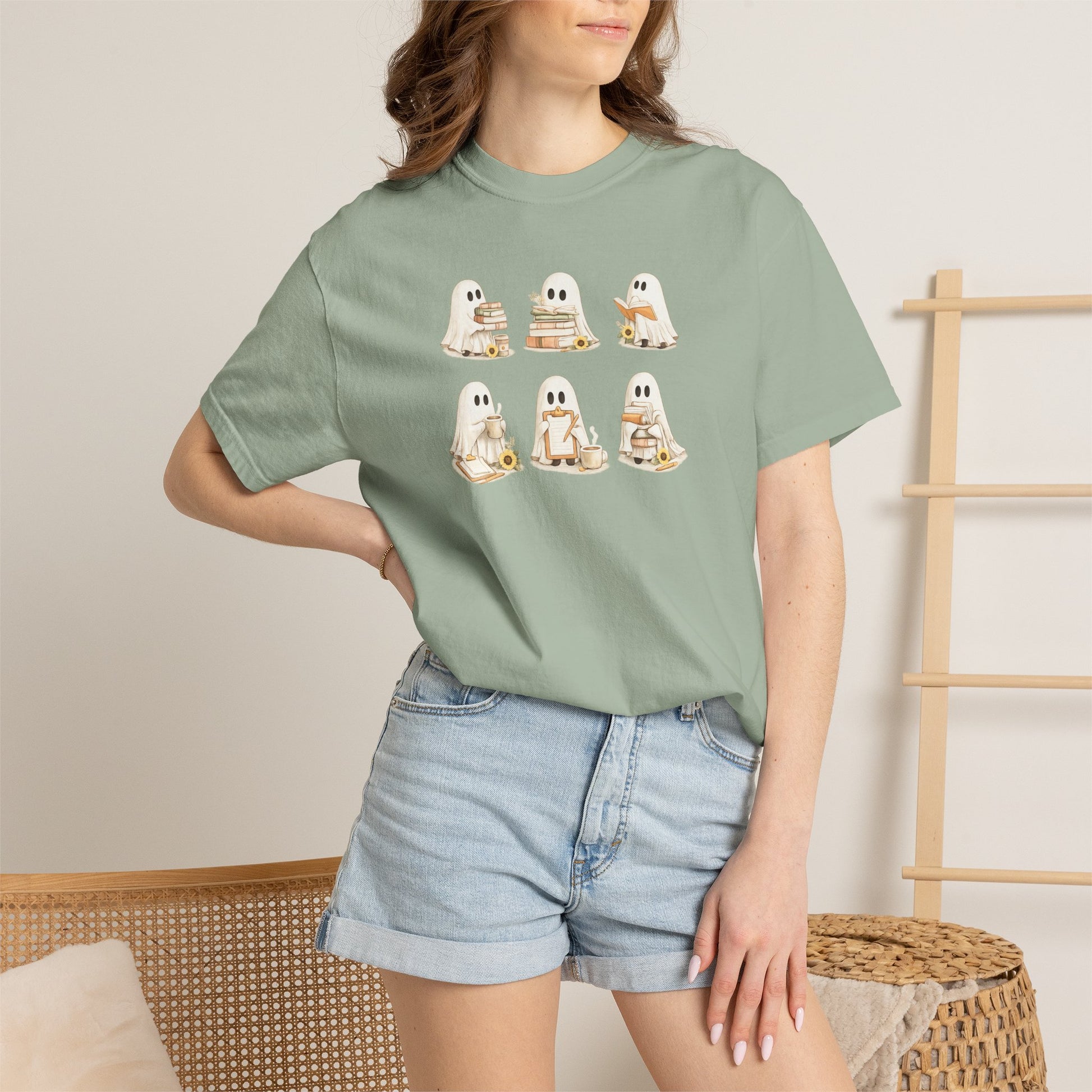 Woman wearing sage green Comfort Colors Ghost Teacher Shirt with hand-illustrated ghosts holding books design - The Teechers Thread