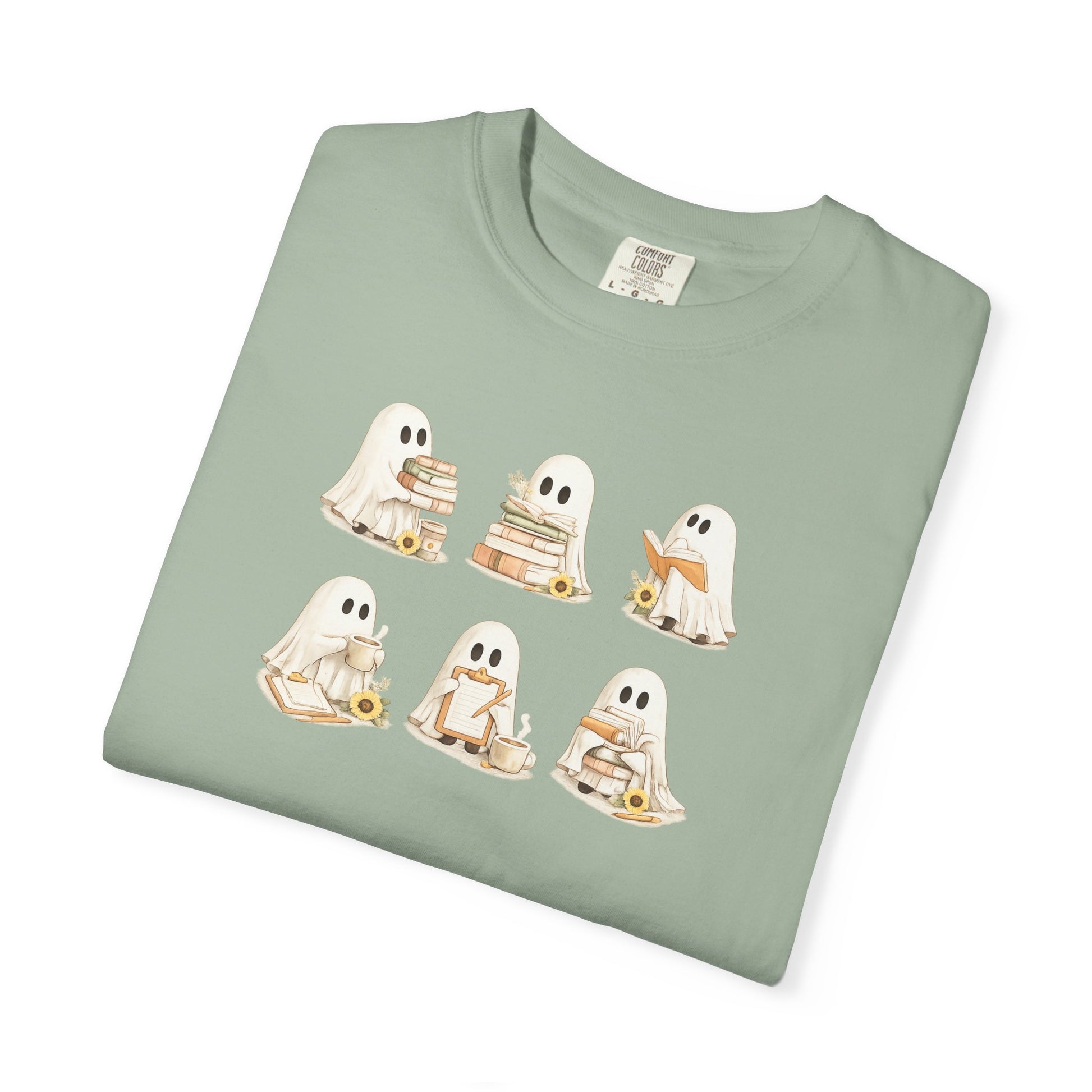Sage green Comfort Colors t-shirt folded flat lay with six hand-illustrated ghosts holding books design - Ghost Teacher Shirt by The Teechers Thread